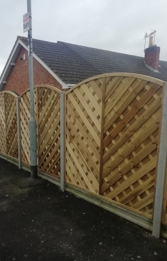 Curved-top lattice panels on concrete posts along a pavement