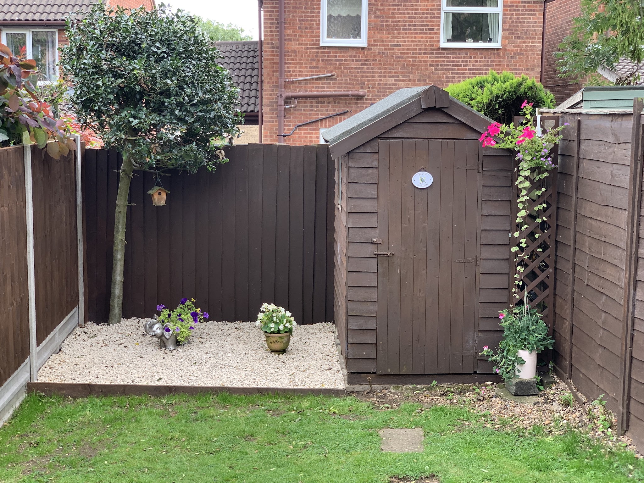 Brown-stained fencing around a small garden with a shed and gravel bed