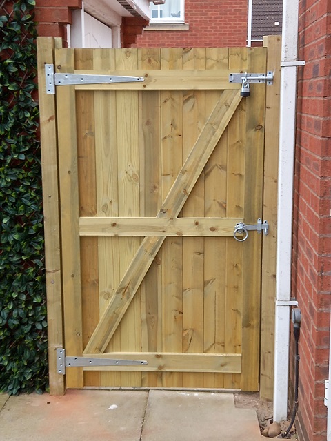 A new ledged and braced wooden side gate with black hinges